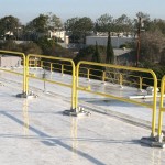 A rooftop guardrail installation using metal railings at the roof edge for maintenance personnel is an example of passive fall protection.